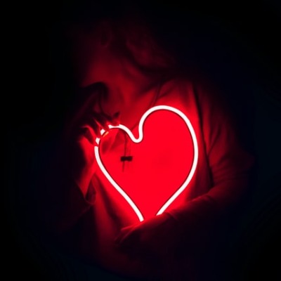 woman holds 'neon' heart over her chest