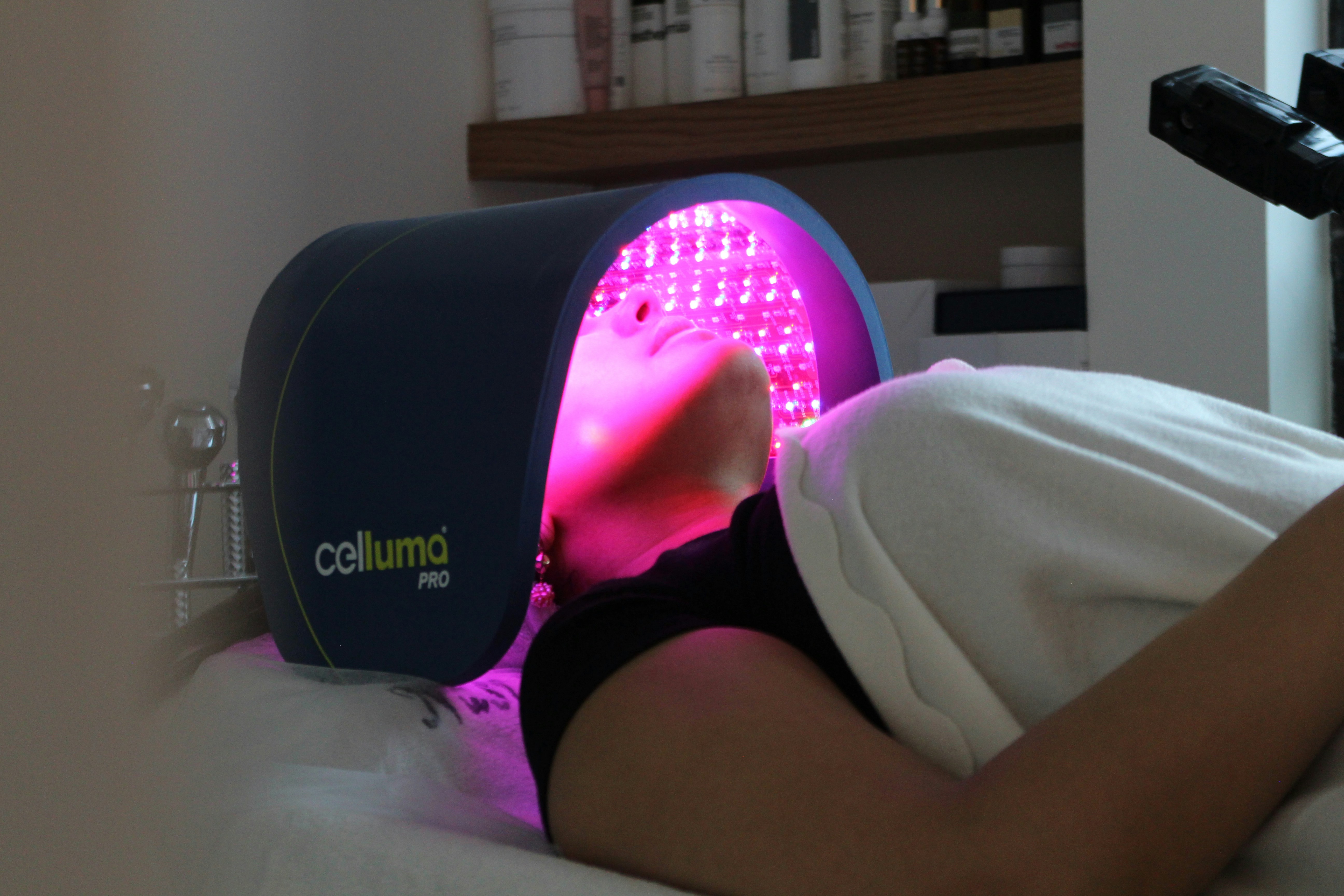 a woman undergoing phototherapy on her face while laying on a bed