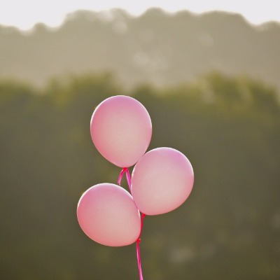 globos rosados flotando con arboles borrosos en el fondo
