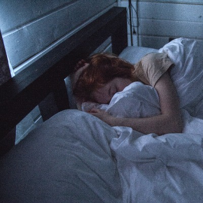 woman sleeping on a bed in a darkened room