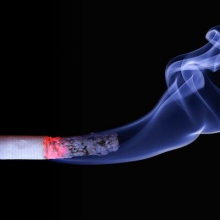 lit cigarette with smoke on black background